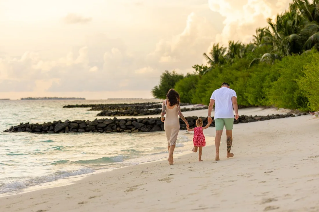 A family enjoying a peaceful beach walk at Embudu Village